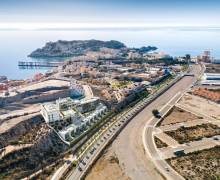Bahía de Águilas con aguas cristalinas, edificios junto al mar y paisaje mediterráneo en un día soleado.